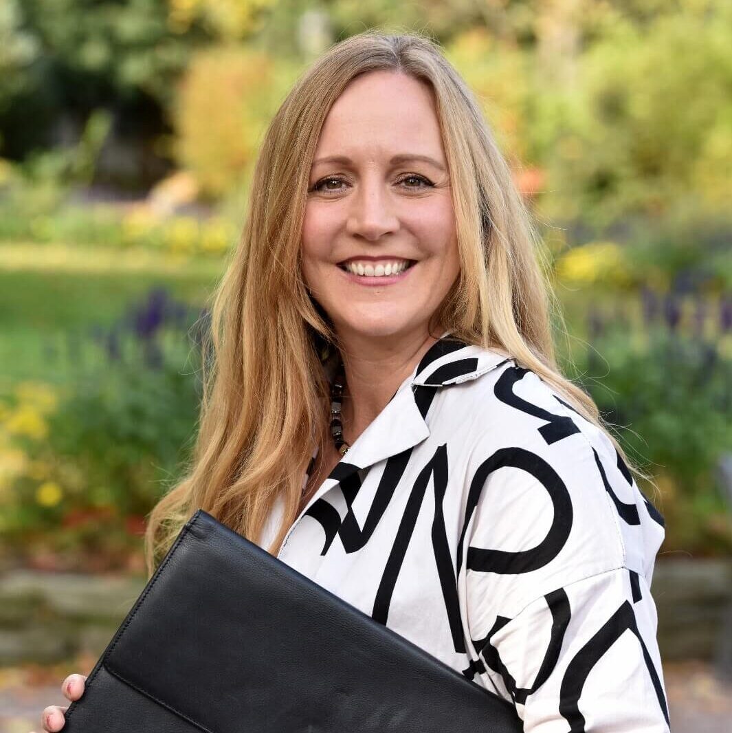 Anna Gloux mit Aktenmappe im Park – Ihre strategische Immobilienmaklerin