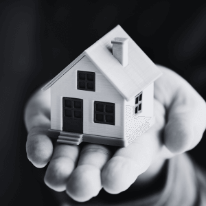 Symbolisches Miniaturhaus auf einer ausgestreckten Hand – Hauskauf mit Vertrauen.